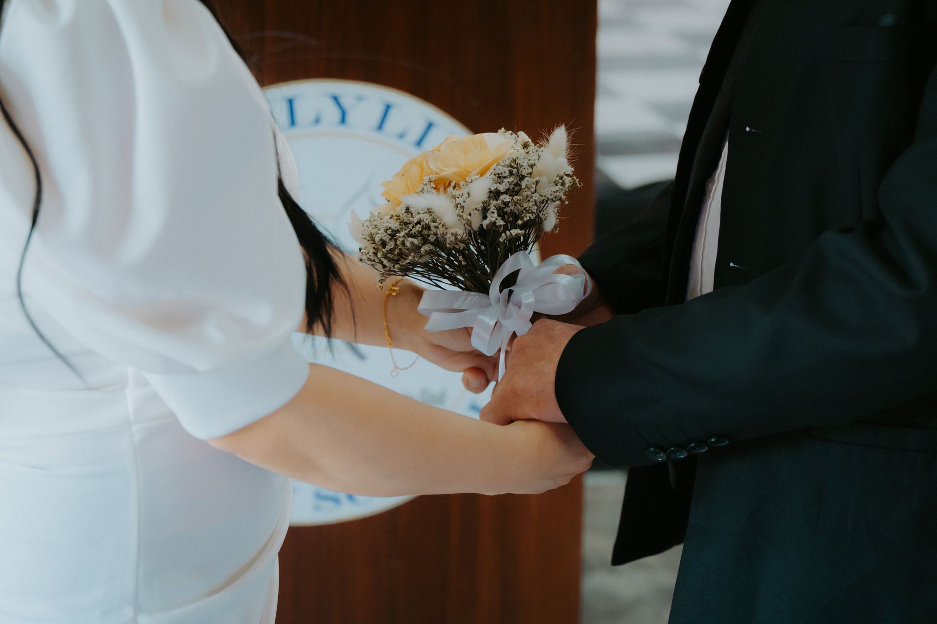 Close-up of a couple holding hands with a bouquet during a wedding ceremony, symbolizing love and commitment.